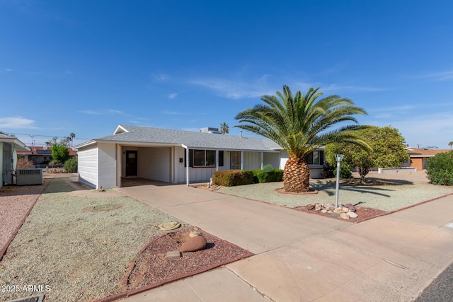 ranch-style home with an attached carport, central AC unit, driveway, and board and batten siding