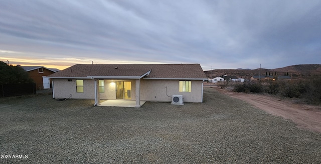 back house at dusk featuring a mountain view and a patio