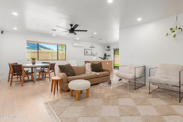 living room featuring a wall unit AC, ceiling fan, and light wood-type flooring