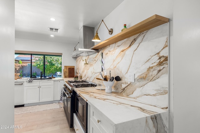 kitchen featuring white dishwasher, range with two ovens, sink, white cabinetry, and light hardwood / wood-style flooring