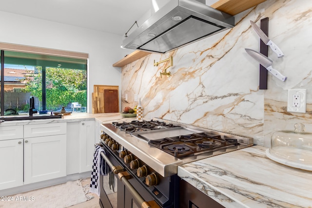 kitchen with white cabinetry, decorative backsplash, range with two ovens, and exhaust hood