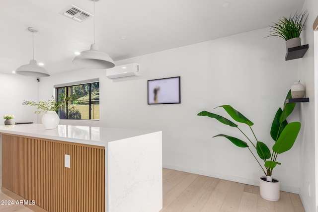 kitchen featuring light hardwood / wood-style floors, a wall mounted AC, and decorative light fixtures