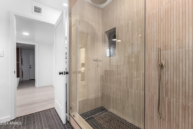 bathroom featuring hardwood / wood-style flooring and tiled shower