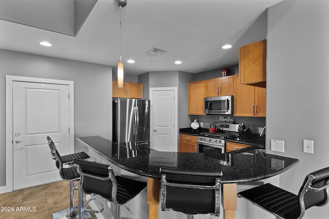 kitchen featuring pendant lighting, stainless steel appliances, kitchen peninsula, and a kitchen bar