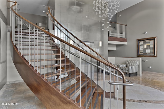 stairway with tile floors and a towering ceiling