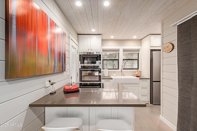 kitchen with a breakfast bar area, white cabinetry, wood ceiling, kitchen peninsula, and stainless steel appliances