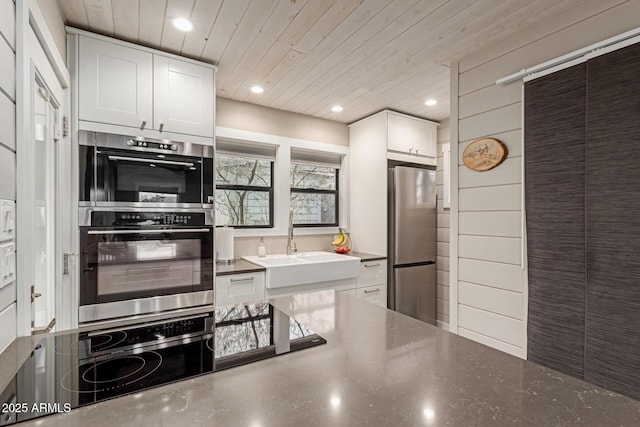 kitchen with wooden ceiling, stainless steel appliances, sink, and white cabinets