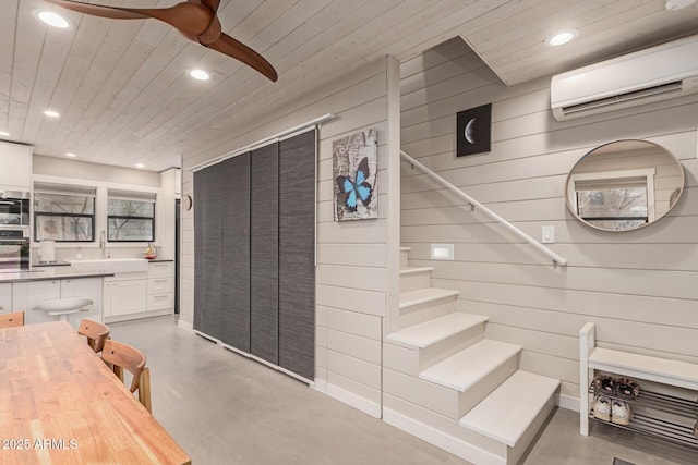 staircase featuring sink, concrete floors, an AC wall unit, and wooden ceiling