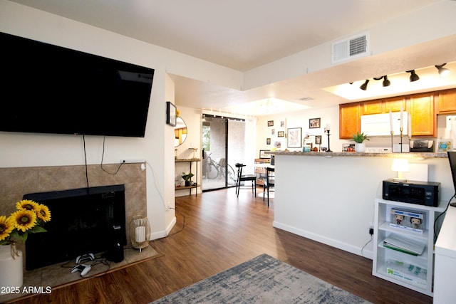 kitchen featuring refrigerator, baseboards, a peninsula, visible vents, and wood finished floors