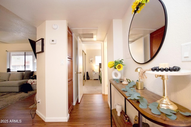 corridor with wood finished floors, baseboards, and visible vents