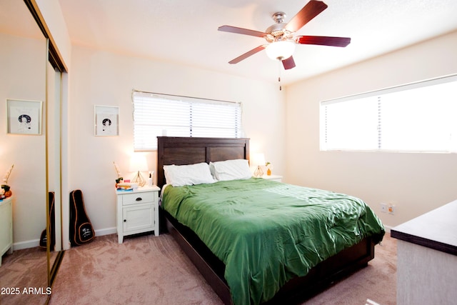 bedroom featuring light carpet, a closet, ceiling fan, and baseboards