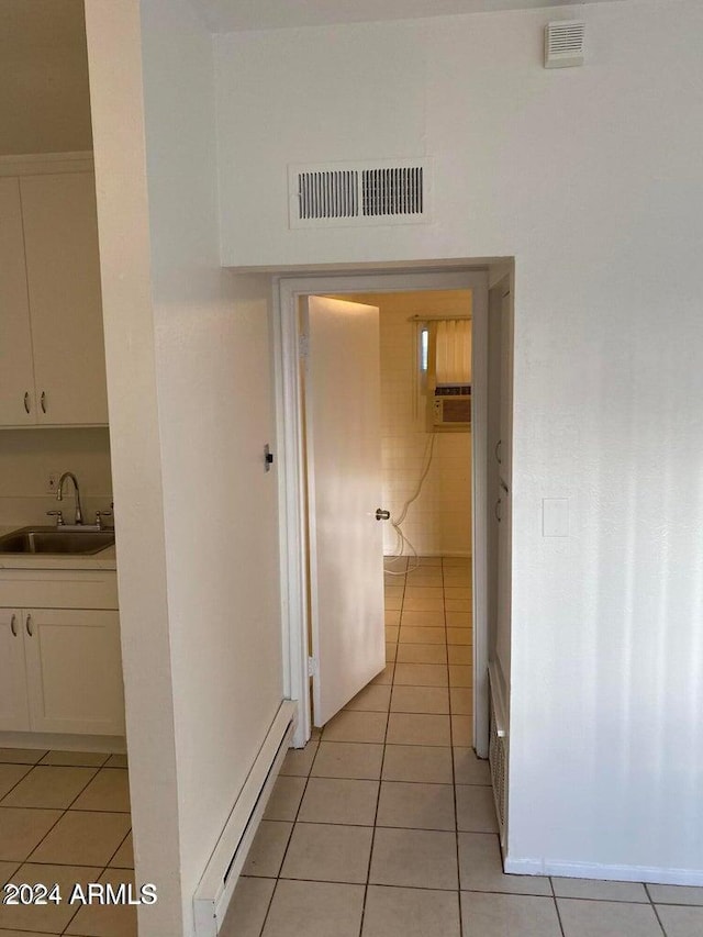 hall featuring light tile patterned flooring, sink, a wall unit AC, and a baseboard radiator