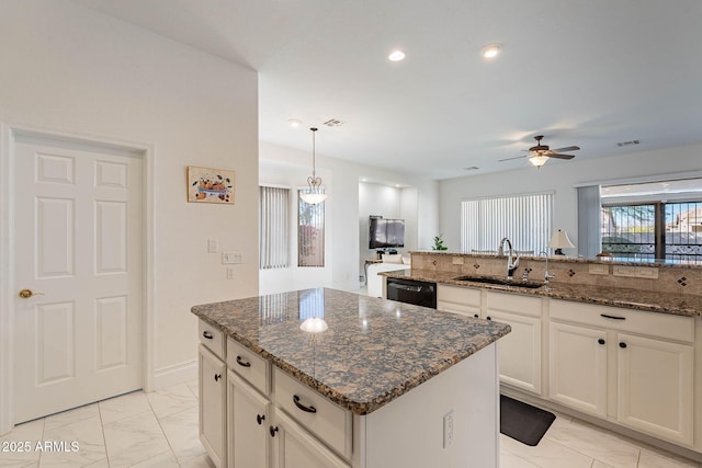 kitchen with dishwasher, a kitchen island, sink, and dark stone countertops