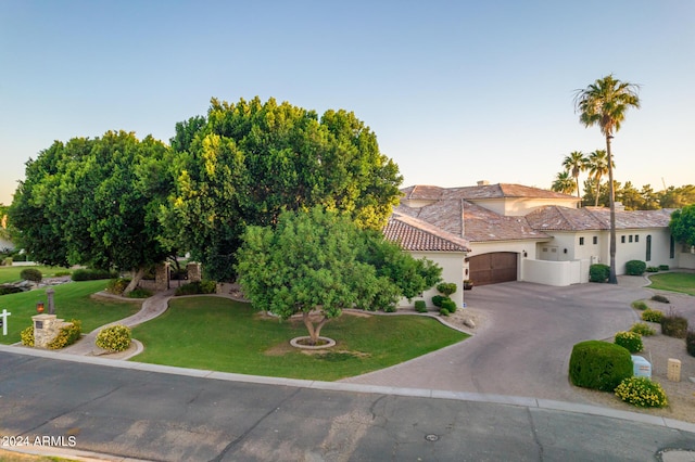 mediterranean / spanish home with a garage and a lawn