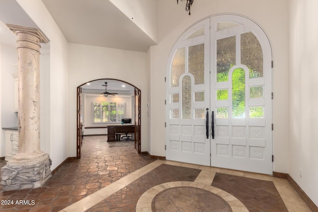 tiled entrance foyer featuring ceiling fan, ornate columns, and french doors