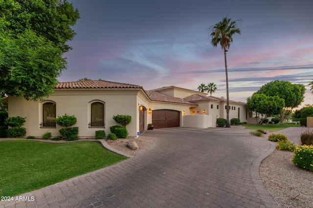 mediterranean / spanish-style home featuring a lawn and a garage