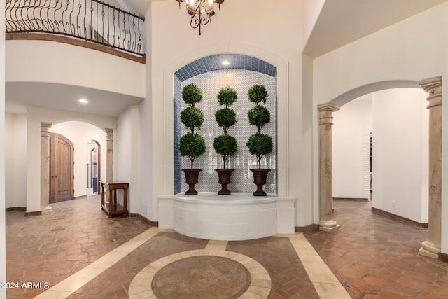 entrance foyer with decorative columns, a high ceiling, and a notable chandelier