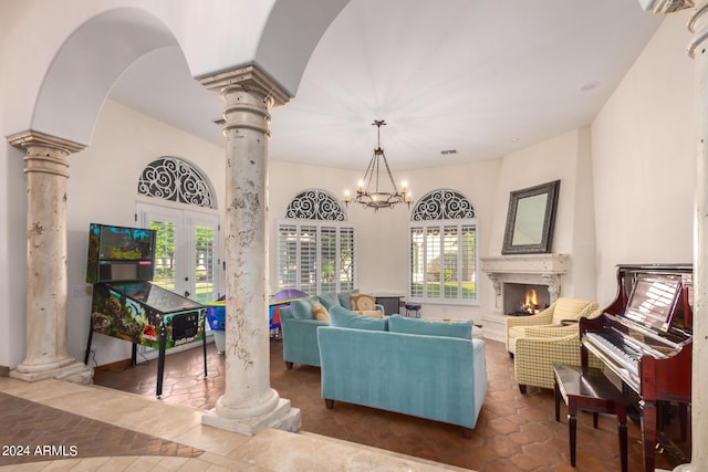 living room featuring ornate columns, french doors, a high end fireplace, and an inviting chandelier