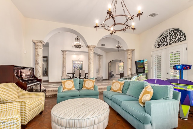 tiled living room featuring french doors, decorative columns, and a notable chandelier