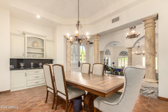 dining room featuring a raised ceiling and ornate columns