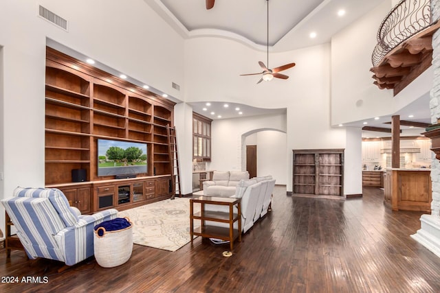 living room featuring ceiling fan, dark hardwood / wood-style flooring, built in features, and a high ceiling