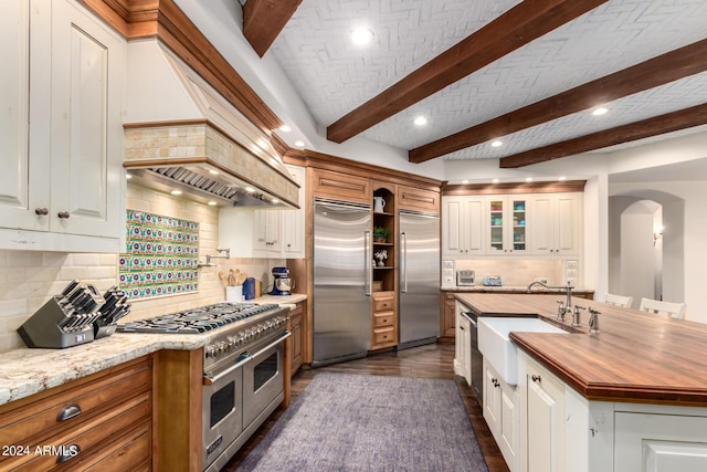 kitchen with wooden counters, premium appliances, white cabinetry, and sink