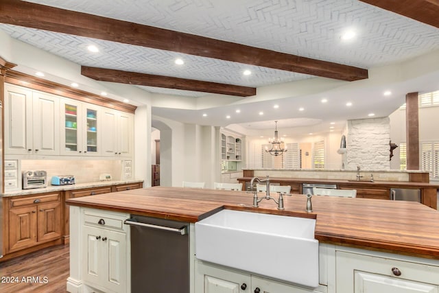 kitchen with backsplash, decorative light fixtures, butcher block counters, and sink