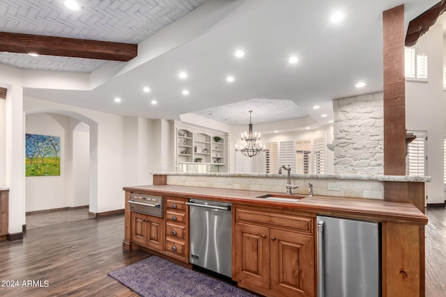 kitchen with sink, dishwasher, butcher block countertops, fridge, and a center island with sink