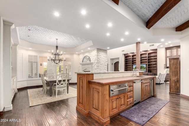 kitchen with dark hardwood / wood-style flooring, a large island with sink, a fireplace, and decorative light fixtures