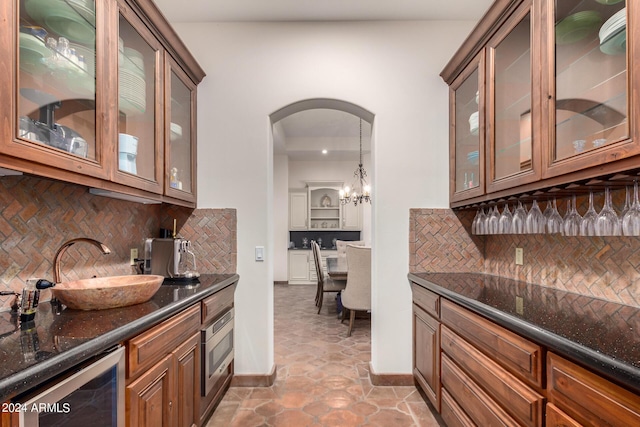 bar with decorative backsplash, decorative light fixtures, and dark stone counters