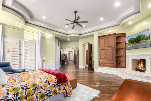 bedroom featuring a raised ceiling, ceiling fan, and dark wood-type flooring