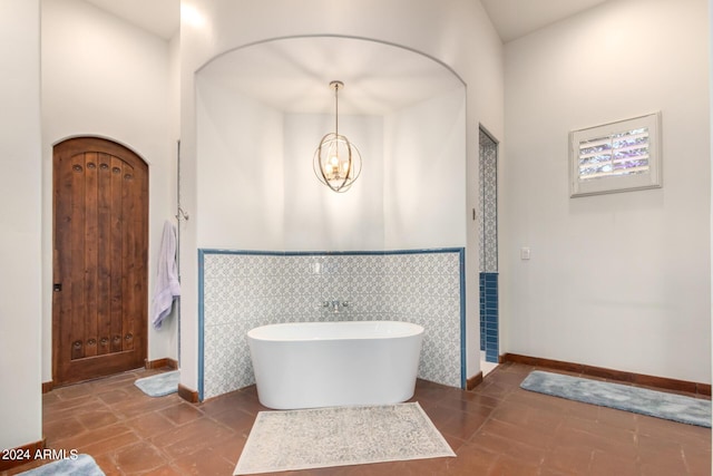 bathroom featuring tile patterned flooring, a bath, tile walls, and an inviting chandelier