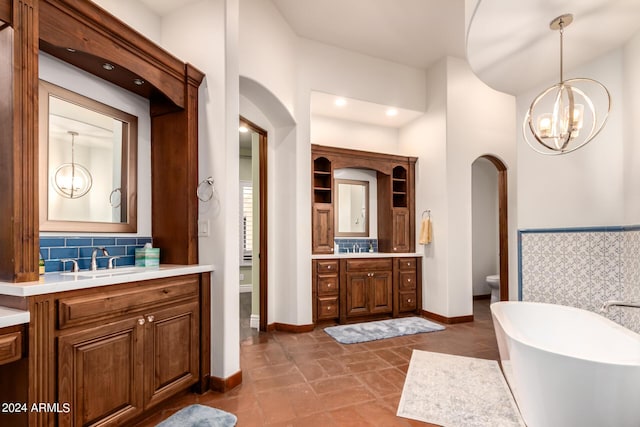 bathroom featuring backsplash, a tub, vanity, and an inviting chandelier