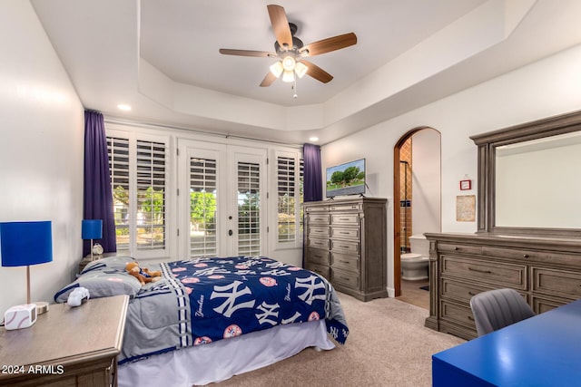 carpeted bedroom with access to exterior, ceiling fan, a raised ceiling, and ensuite bathroom