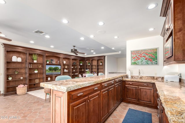 kitchen featuring ceiling fan, light stone countertops, kitchen peninsula, and sink