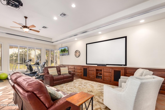 home theater room with a raised ceiling and ceiling fan