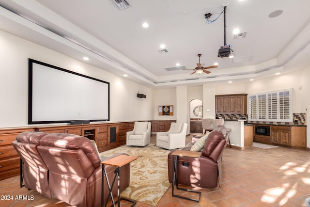 cinema featuring ceiling fan and a tray ceiling