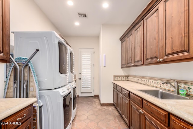 washroom with stacked washer / drying machine, light tile patterned flooring, cabinets, and sink