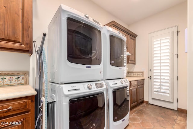 washroom featuring light tile patterned floors, cabinets, and stacked washer / drying machine