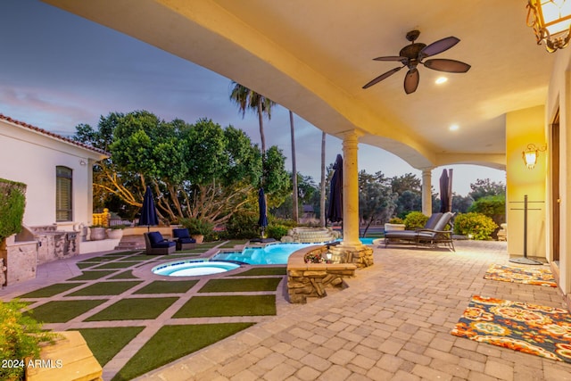 patio terrace at dusk featuring area for grilling, ceiling fan, and a pool with hot tub