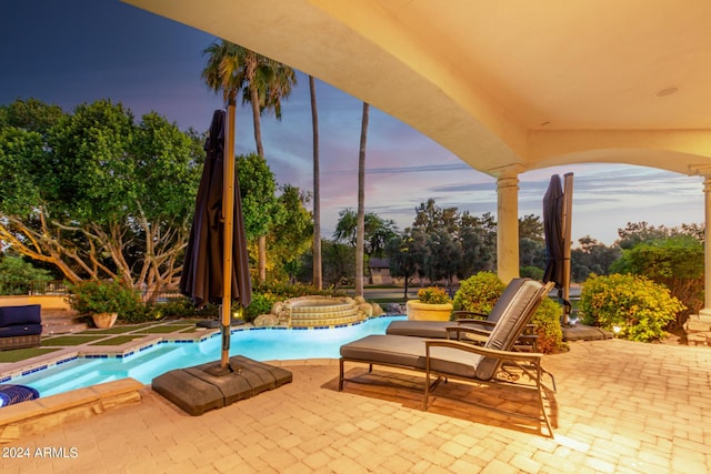 pool at dusk featuring a patio area