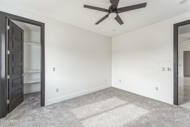 unfurnished bedroom with ceiling fan, a walk in closet, and carpet