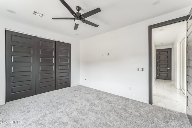 unfurnished bedroom featuring light carpet, ceiling fan, and a closet