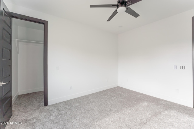 unfurnished bedroom featuring a closet, light colored carpet, and ceiling fan