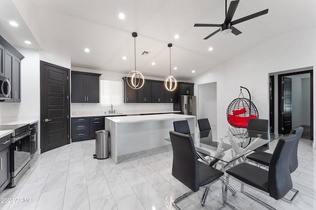 kitchen featuring lofted ceiling, a center island, hanging light fixtures, sink, and appliances with stainless steel finishes