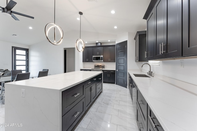 kitchen with light stone counters, appliances with stainless steel finishes, a large island, pendant lighting, and sink