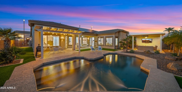 back of house at dusk featuring fence, roof mounted solar panels, stucco siding, an outdoor pool, and a patio