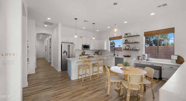 kitchen with tasteful backsplash, visible vents, a center island, arched walkways, and stainless steel appliances