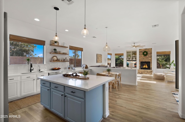 kitchen featuring a center island, light countertops, a fireplace, light wood-style floors, and a sink