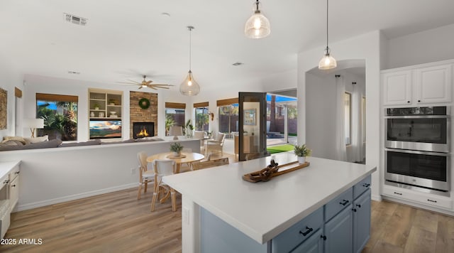 kitchen featuring stainless steel double oven, light wood-style flooring, visible vents, and open floor plan